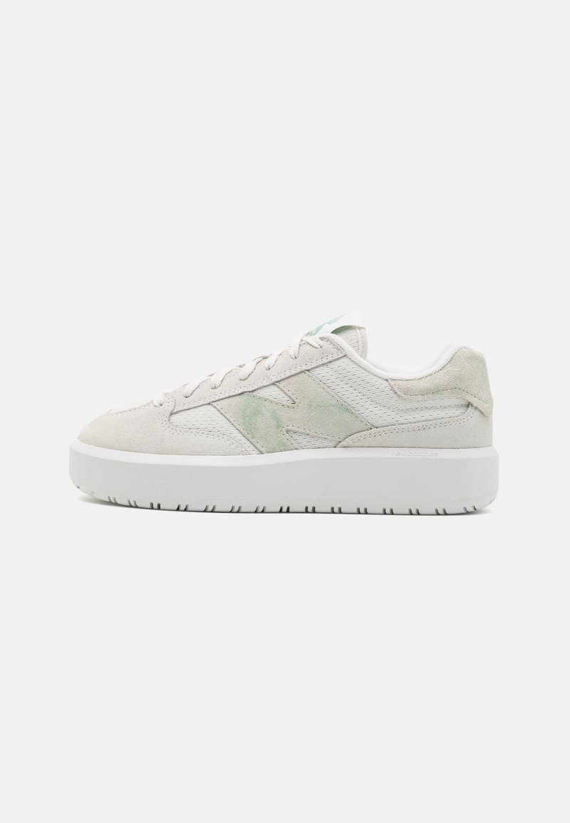 Baskets basses beige en suède et mesh, lacets sur le devant, marquage vert sur le côté et semelle épaisse en caoutchouc blanc.