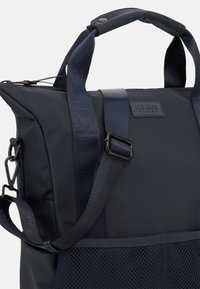 Borsa tote blu navy con tessuto strutturato, dotata di manici resistenti, tracolla staccabile e una tasca in rete lungo il bordo inferiore.