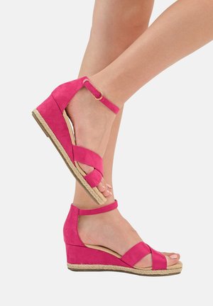 Sandales compensées en daim rose avec des brides croisées, bout ouvert, bride de cheville avec boucle, et semelle plateforme en jute.