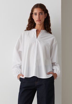 Witte langemouwen shirt met een gespleten kraag en gathered manchetten, met een rechte zoom. Gepaard met donkerblauwe denim broek.