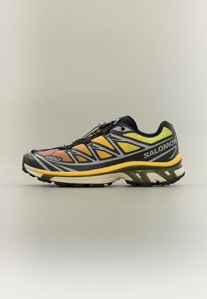 Chaussure de trail running jaune, orange et noire avec système de laçage rapide et semelle robuste, portant la marque Salomon sur le côté.