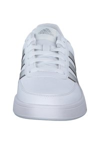 White synthetic sneakers with three silver stripes, round toe, lace-up design, and textured rubber sole. Features perforated detailing.