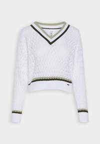 Vit stickad tröja med V-hals. Har gröna och mörkgröna randiga detaljer vid halsringningen och ärmarna. Cropped stil med texturerat mönster.