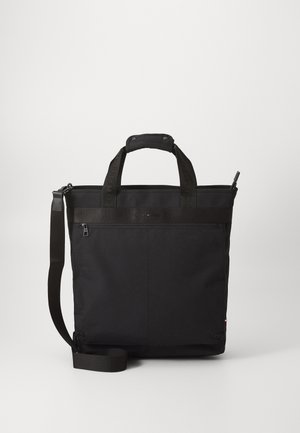 Sac à épaule rectangulaire noir avec poignées supérieures, poche zippée à l'avant et bandoulière réglable sur fond clair uni.