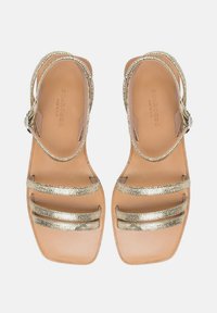 Zlatne sandale sa remenčićima i ravnim potplatom, s glatkom kožnom uložkom i tri metalna remena preko stopala za potporu.