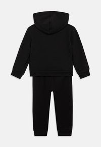 Conjunto de sweatshirts com capuz preto e calças de fato combinando, com punhos canelados, mostrado de costas num fundo branco.