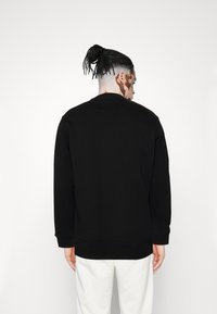 Sort sweatshirt med rund hals og lange ærmer, med ribbede manchetter og nederste kant. Glat tekstur med et minimalistisk design.