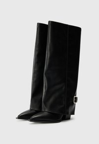 Bottes noires en cuir jusqu'au genou avec un bout pointu, une texture lisse et un détail de boucle sur le côté. Design à talon plat.