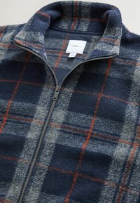 Fleece-Trainingsjacke mit einem karierten Muster in Marineblau, Grau und Orange, mit Stehkragen und silbernem Reißverschluss-Akzent.