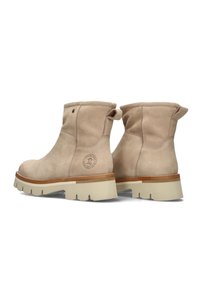 Botas de tobillo de cuero beige con una textura suave, punta redonda y suela plana con un dibujo de goma de color claro. Logo grabado en el lateral.