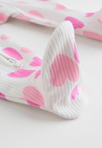 Białe prążkowane skarpetki z dużymi różowymi sercami. Teksturowany materiał z zaokrąglonym noskiem i lekko elastycznym zakończeniem przy otworze.