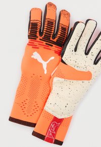 Ζευγάρι γάντια τερματοφύλακα πορτοκαλί και άσπρου χρώματος με μαύρα στίγματα, μαύρες άκρες δακτύλων και λογότυπο Puma σε λευκό στο πίσω μέρος του χεριού.