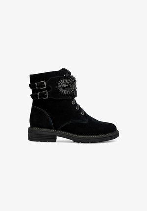 Bottines en suede noir avec une double sangle à boucle, ornées d'un détail en gemme noire décorative, un petit talon empilé et un design à bout rond.
