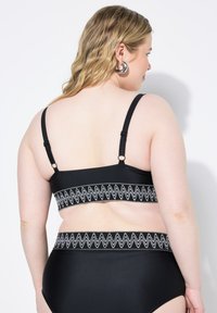 Completo bikini nero con una fascia zigzag argentata testurizzata sia sopra che sotto. Spalline regolabili sulla parte superiore per una vestibilità ottimale. Tessuto liscio.