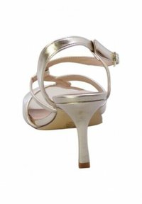 Sandal alto in metallo argento con più cinturini incrociati, tacco sottile e soletta liscia. Dettaglio della chiusura a fibbia visibile.