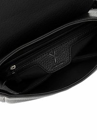 Wnętrze czarnej skórzanej torebki z teksturowaną kieszenią na zamek, gładką podszewką i tłoczonym logo marki. Charakteryzuje si�ę eleganckim, uporządkowanym designem.