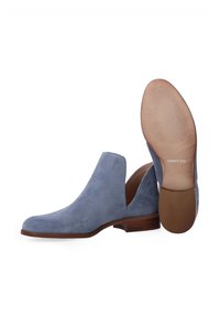 Helles blaues Wildleder-Ankle-Boot mit spitzem Zehenbereich, niedrigem Absatz und ausgeschnittenen Seiten. Verfügt über eine braune Sohle mit Rillen und einem "made in Italy"-Label.