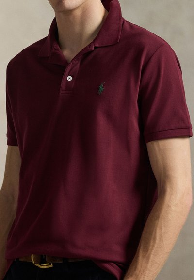 Burgunderfarget pikéskjorte i pustende bomull, med klassisk krage, korte ermer og en liten grønn logo på venstre bryst.