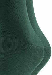 Dunkelgrüne Baumwollsocken mit gerippter Struktur, die eine glatte Oberfläche und verstärkte Zehen- und Fersenbereiche aufweisen.