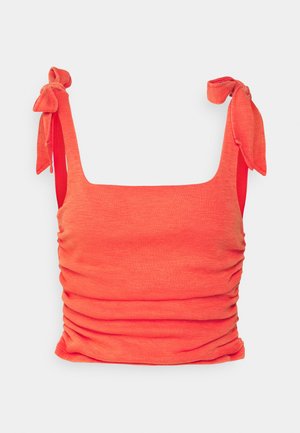Top cropped em coral, feito de tecido canelado, com decote quadrado, laterais franzidas e alças ajustáveis com laço.