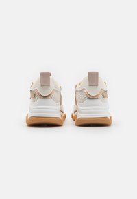 Chunky Sneaker mit einem weißen Mesh-Obermaterial und beigen Akzenten, ausgestattet mit einer strukturierten Gummi-Außensohle und einem Schlaufen-Zugband für einfaches Anziehen.