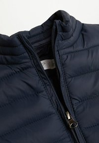 Námořnická puffy bunda s prošívaným designem, vysokým límcem a zapínáním na zip. Vyrobena z lehkého, hladkého materiálu.