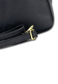 Zwarte leren tas met een gestructureerde afwerking, voorzien van een gouden hardware-accent en een verstelbare schouderband. Compact ontwerp met een platte vorm.