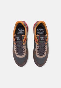 Zapatillas deportivas con parte superior de malla gris, acentos de ante marrón, detalles de cuero naranja y cordones negros. Presenta una suela acolchada y marca.