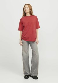 Rød bomull t-skjorte med korte ermer, avslappet passform, rund hals. Kombinert med lysegrå vide jeans og svarte platå sko.