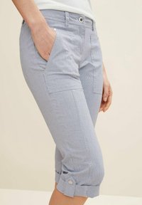 Pantalones capri a rayas azul claro, hechos de tela texturizada. Presentan bolsillos laterales y puños enrollados asegurados con botones.