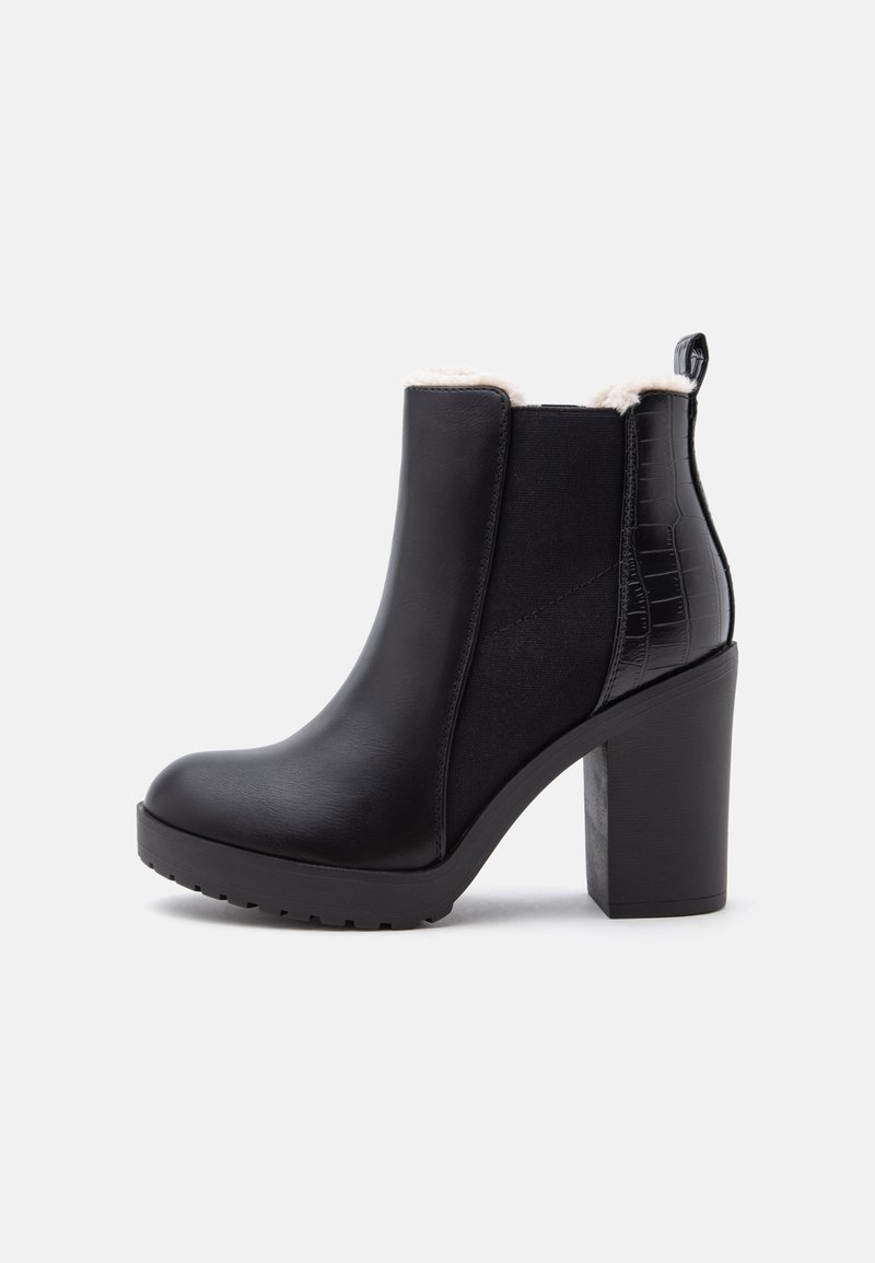 Bottine noire à la cheville avec talon haut épais, panneau latéral élastique, bordure en fausse fourrure à l'intérieur et détail texturé au dos.