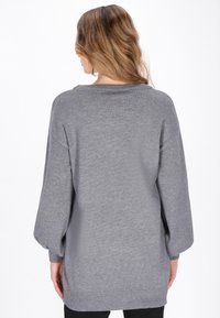 Grau gestrickter Pullover mit lässiger Passform, weiten Ärmeln, tiefem Rundhalsausschnitt und geripptem Saum. Weiche Textur, minimalistisches Design, keine auffälligen Muster.