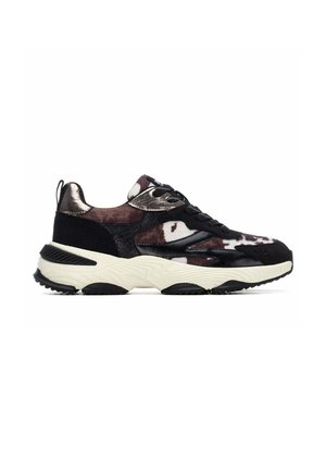 Zapatilla chunky con patrón de estampado de vaca en negro, marrón y blanco, detalles metálicos, cordones negros y suela blanca gruesa con dibujo en negro.