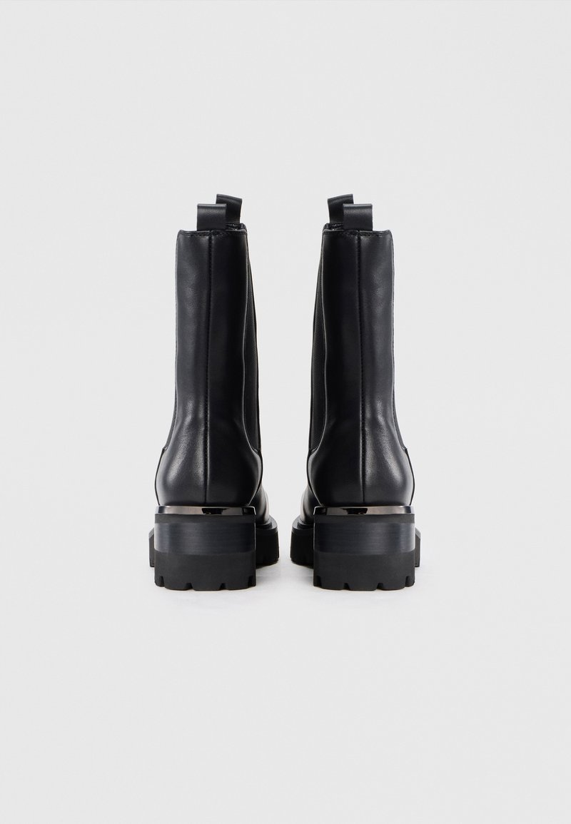 Botas de tobillo de cuero negro con un acabado suave, lengüetas para tirar y suela de goma gruesa con un patrón texturizado para mejor agarre.