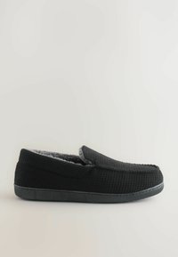 Crne papuče s teksturiranim materijalom, sivi flis podstavljene unutrašnjosti i ravnim gumenim potplatom. Dizajn koji se lako obuva s zaobljenim vrhom i minimalističkim stilom.