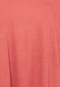 Koralinvärinen pellavasekoitekangas, kevyt, hieman teksturoitu ja pehmeä viimeistely. Sujuva laskos, ei selkeitä kuvioita tai varusteita näkyvissä.