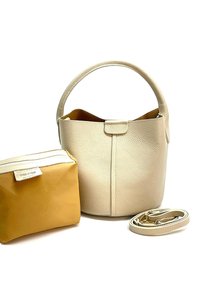 Leren handtas in crème met een getextureerde afwerking, voorzien van een ronde handgreep en een decoratieve flap. Inclusief een kleine gele tas en een schouderband.