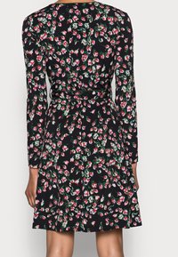 Svart blommig klänning med lång ärm, prydd med ett mönster av röda och gröna blommor. Inkluderar en åtstramad midja och design med utsvängd kjol.