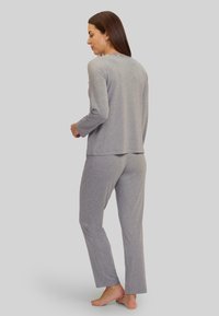 Top de manga larga gris y pantalones a juego hechos de una tela ligera. El conjunto presenta un ajuste relajado y un diseño minimalista, sin patrones visibles.