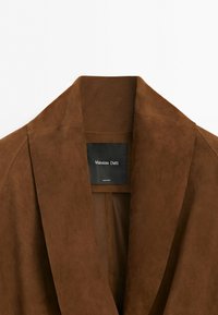 Hnědá semišová bunda se širokým klopovým límcem a černou štítkem s nápisem Massimo Dutti vyrobeno v Indii.
