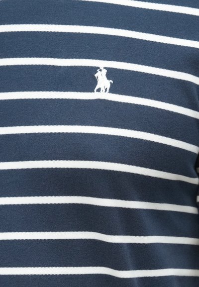 Tumši zils kokvilnas krekls ar baltām horizontālām svītrām, kreisajā krūtīs izšūta zirga un jātnieka logo.