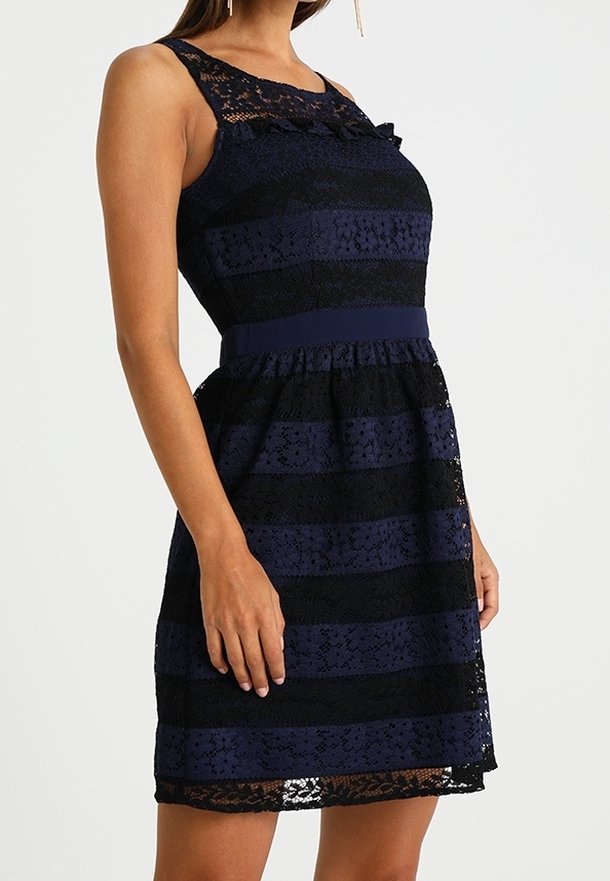 Robe en dentelle rayée marine et noire avec un corsage ajusté, un col à volants et une taille ceinturée, dotée d'une jupe évasée et d'un design sans manches.