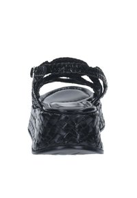 Sandal con cinturino intrecciato nero che presenta una suola a zeppa spessa e una soletta imbottita. La texture appare liscia con una finitura lucida.