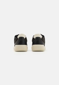 Black suede and leather sneakers with beige accents, featuring a textured rubber sole and brand logo on the heel.