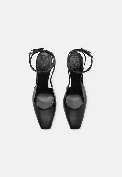 Zapatos de tacón alto de cuero negro con un diseño de punta cuadrada, tira para el tobillo y textura suave. Presenta un logo sutil en la planta.