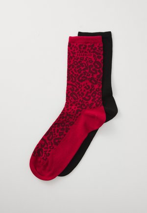 Pair of socks, one solid black and one red with black leopard print pattern, laid flat on a white background.
