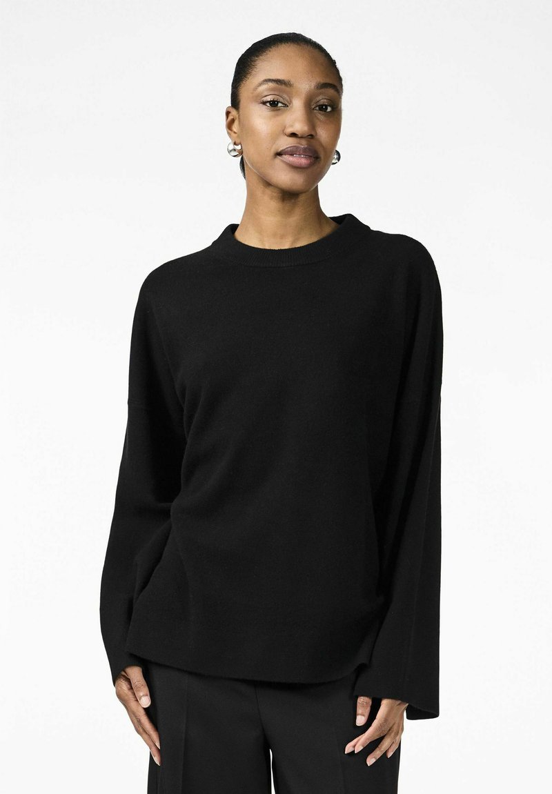 Maglione nero a maniche lunghe con scollo rotondo e vestibilità comoda. Realizzato in tessuto morbido, presenta maniche ampie e un design minimalista.