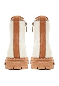 Białe skórzane botki za kostkę z brązowymi bocznymi paskami, teksturowanymi gumowymi podeszwami i dekoracyjnym szyciem. Posiadają zamek błyskawiczny z tyłu.