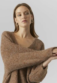Brun strikket sweater med dyb V-udskæring, brede ærmer og en blød tekstureret overflade. Stof synes let og luftigt.