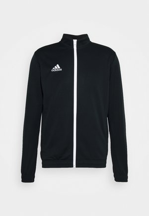 Casaco atlético preto com um fecho branco, gola alta e logo de três riscas no lado esquerdo do peito. Feito de um tecido liso e leve.